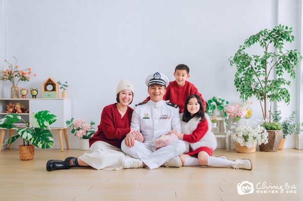 爸爸穿著制服，和媽媽與兩個孩子坐在地上